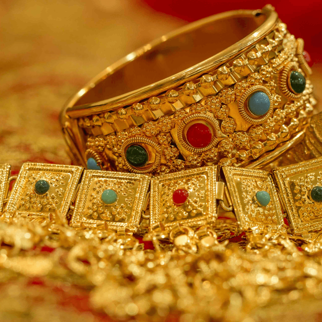 Detailed gold wedding jewellery: a stone-set bangle resting on a necklace of square gold links