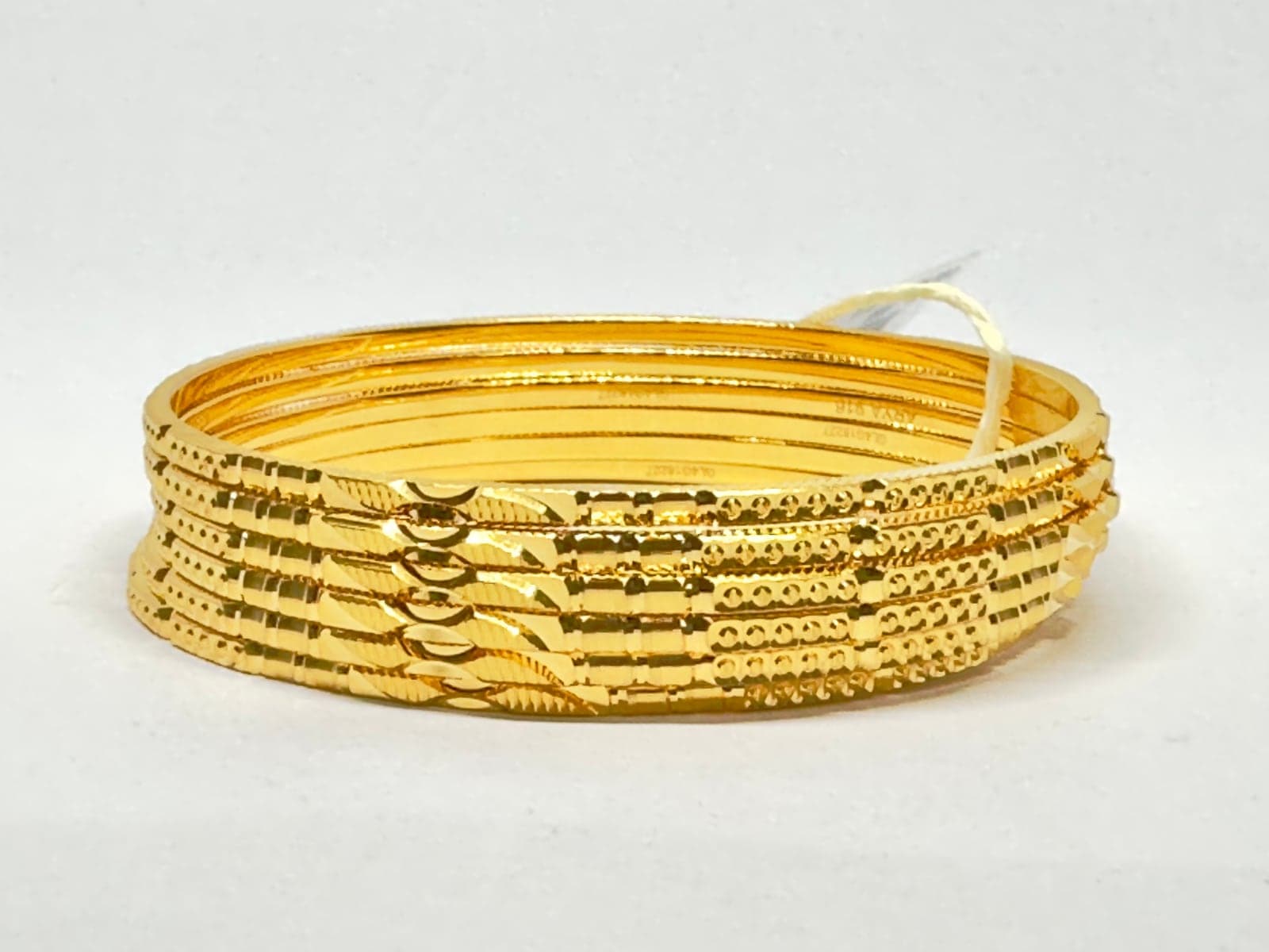 A stack of slim 22ct gold bangles with diamond-cut patterns