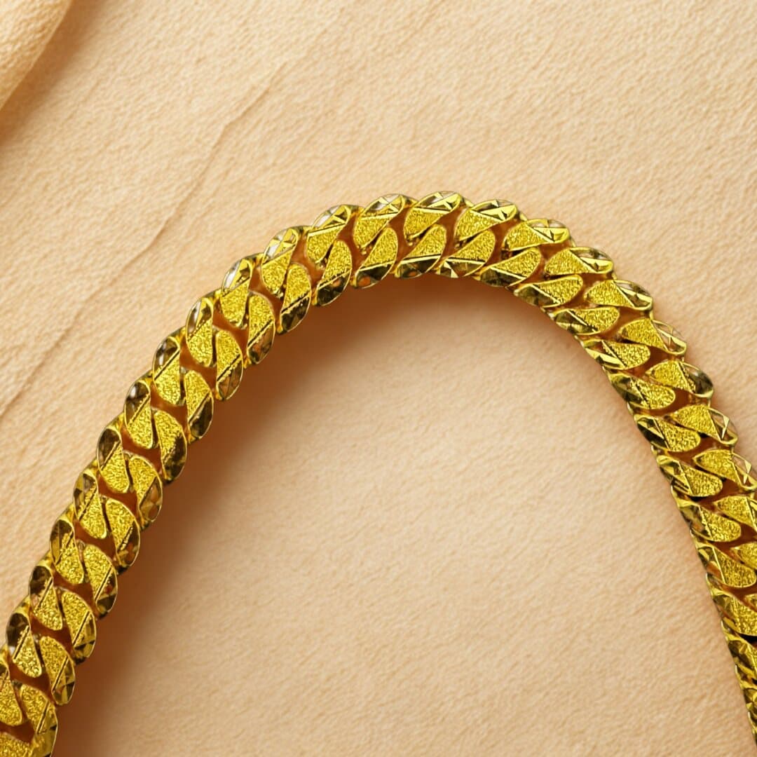 Close-up of a heavy 22ct gold curb chain with sandblast and diamond-cut links