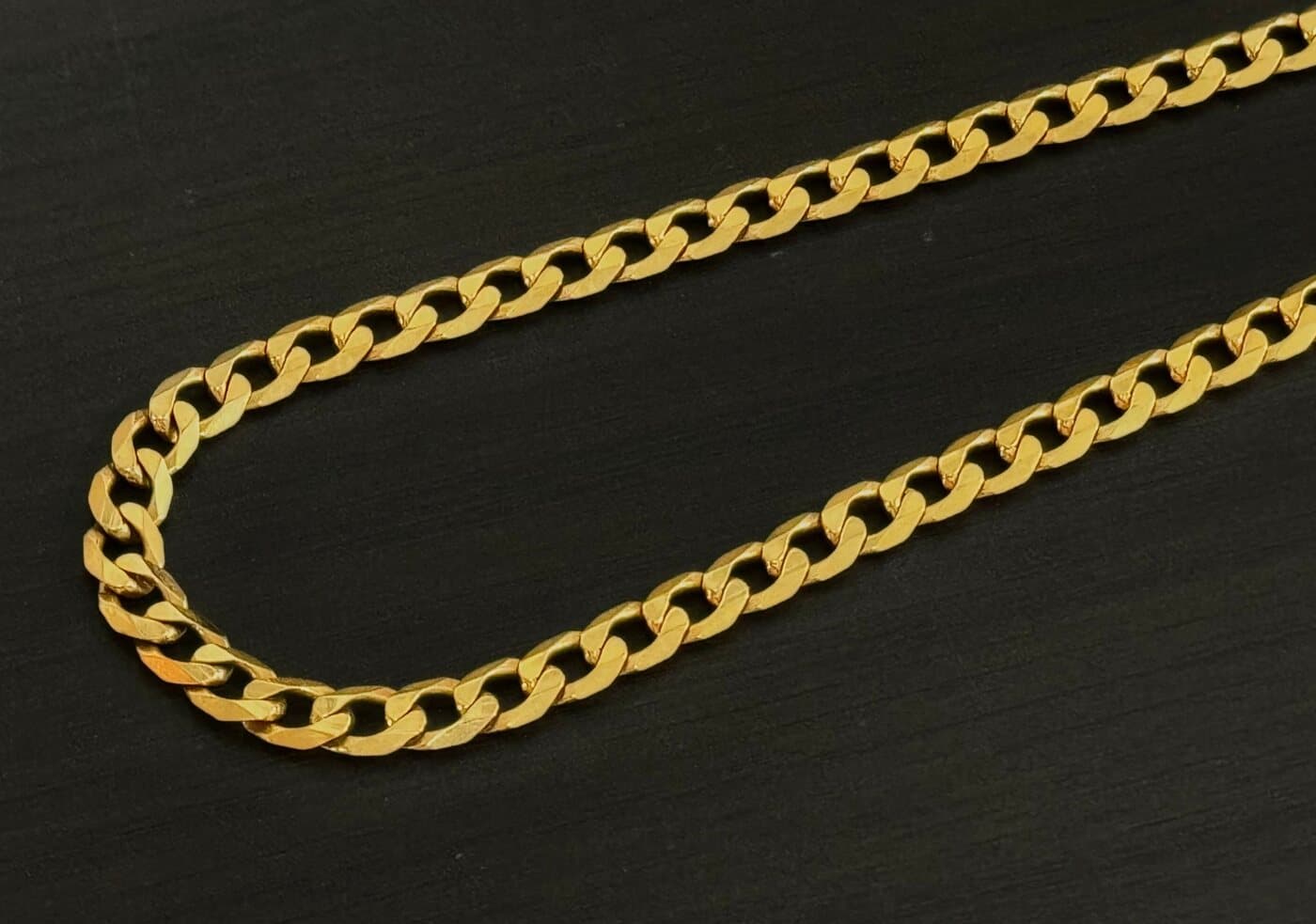 A 22ct gold curb chain on black