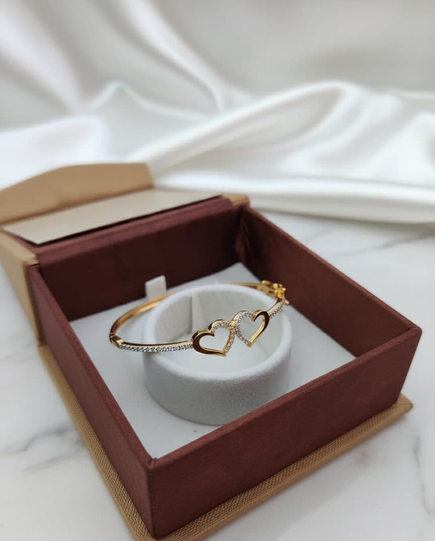 A slim gold bangle with two open hearts, in a gift box