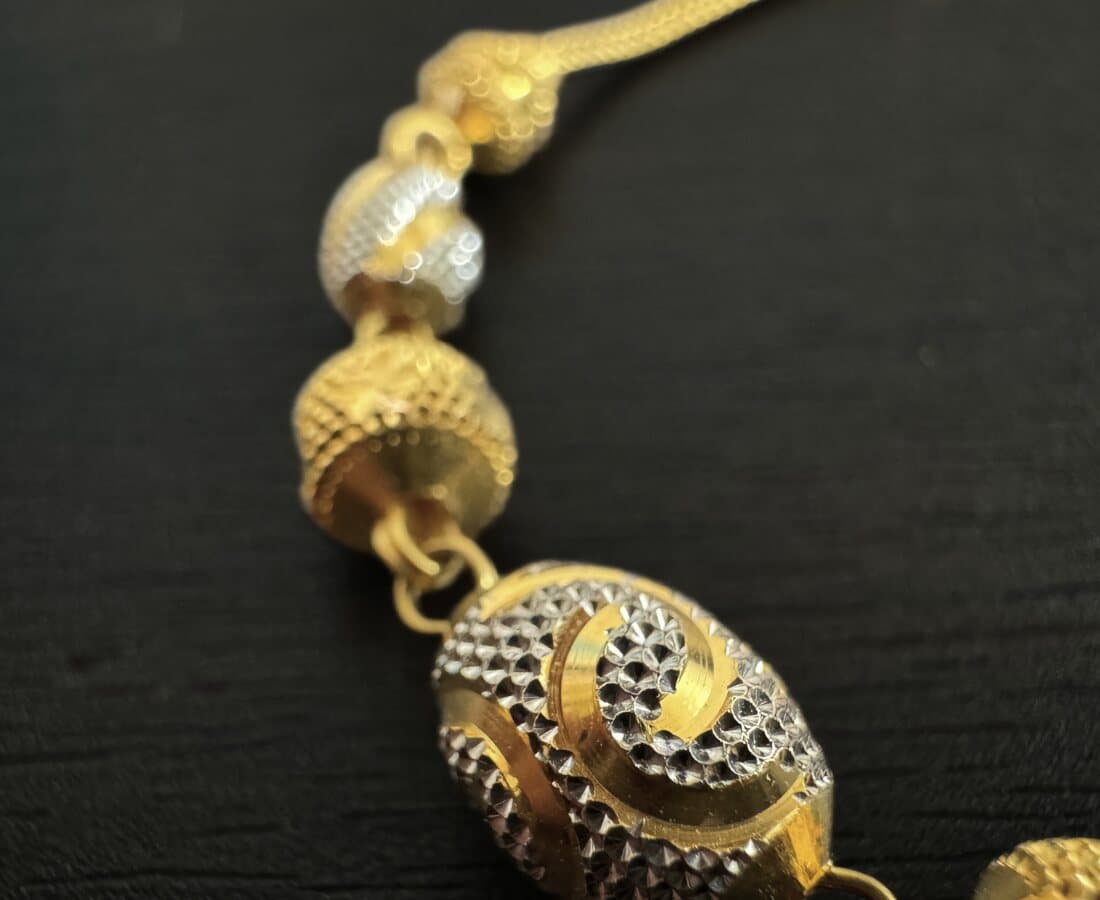 Close-up of two-tone 22ct gold beads with a diamond-cut swirl