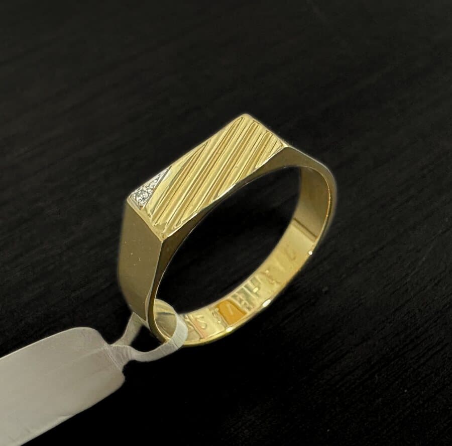 A men’s gold signet ring with a ribbed top and a small diamond